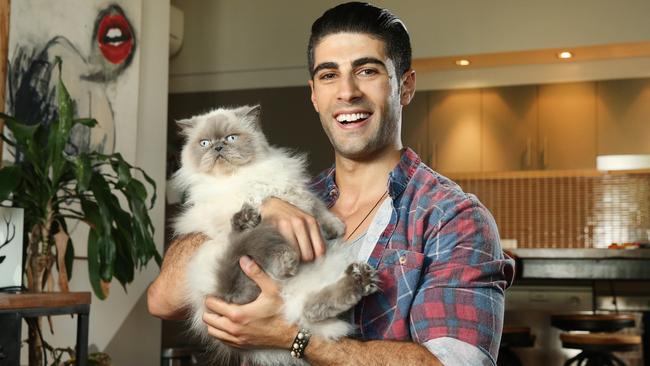 Ibby Moubadder with his cat Belle. His story is an extraordinary one of rags to riches. Picture: Richard Dobson