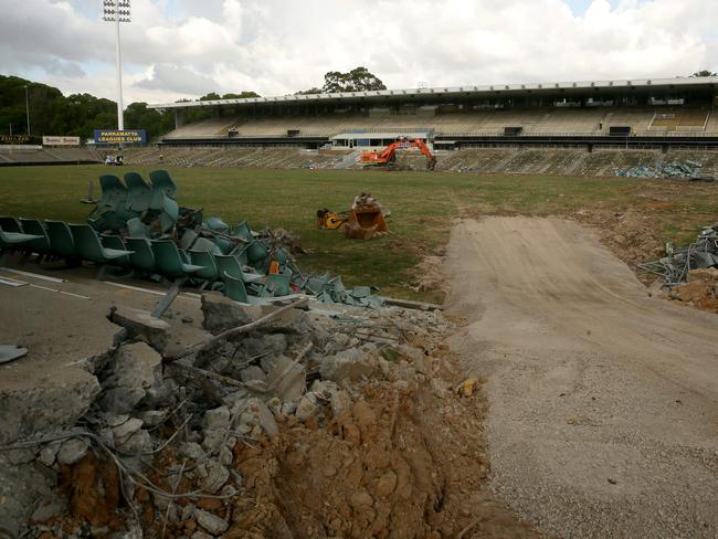 An excavator at the rear of the photo and a track leading in where part of the grand stand was.