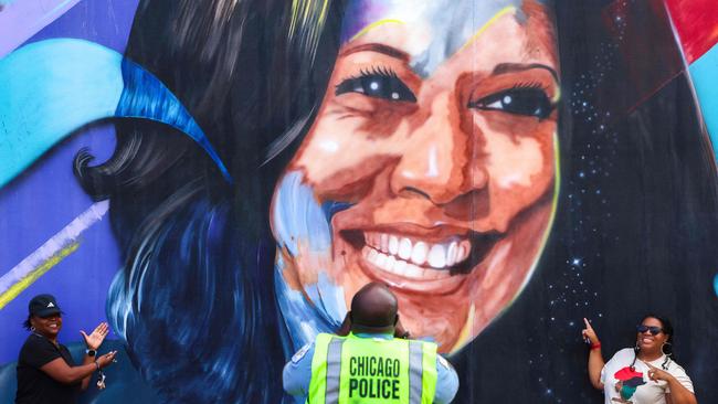 A Chicago police officer takes a picture of people posing before a mural of Kamala Harris outside the United Centre in Chicago. Picture: AFP