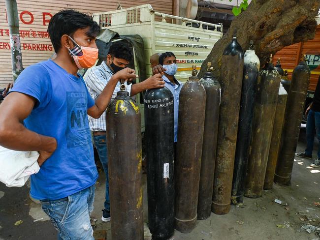 People wait to refill medical oxygen cylinders for COVID-19 patients at a private refill centre in New Delhi. Picture: AFP