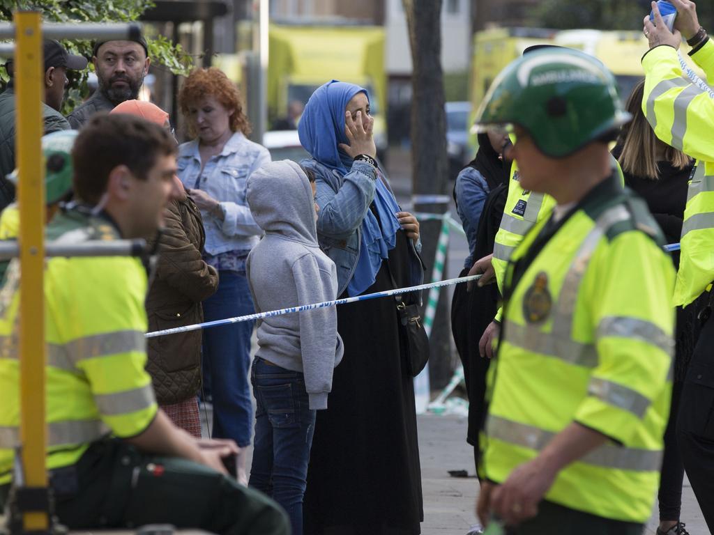 Emergency service responders and locals gather at a cordon near the site of the massive fire. Picture: Rick Findler/PA via AP