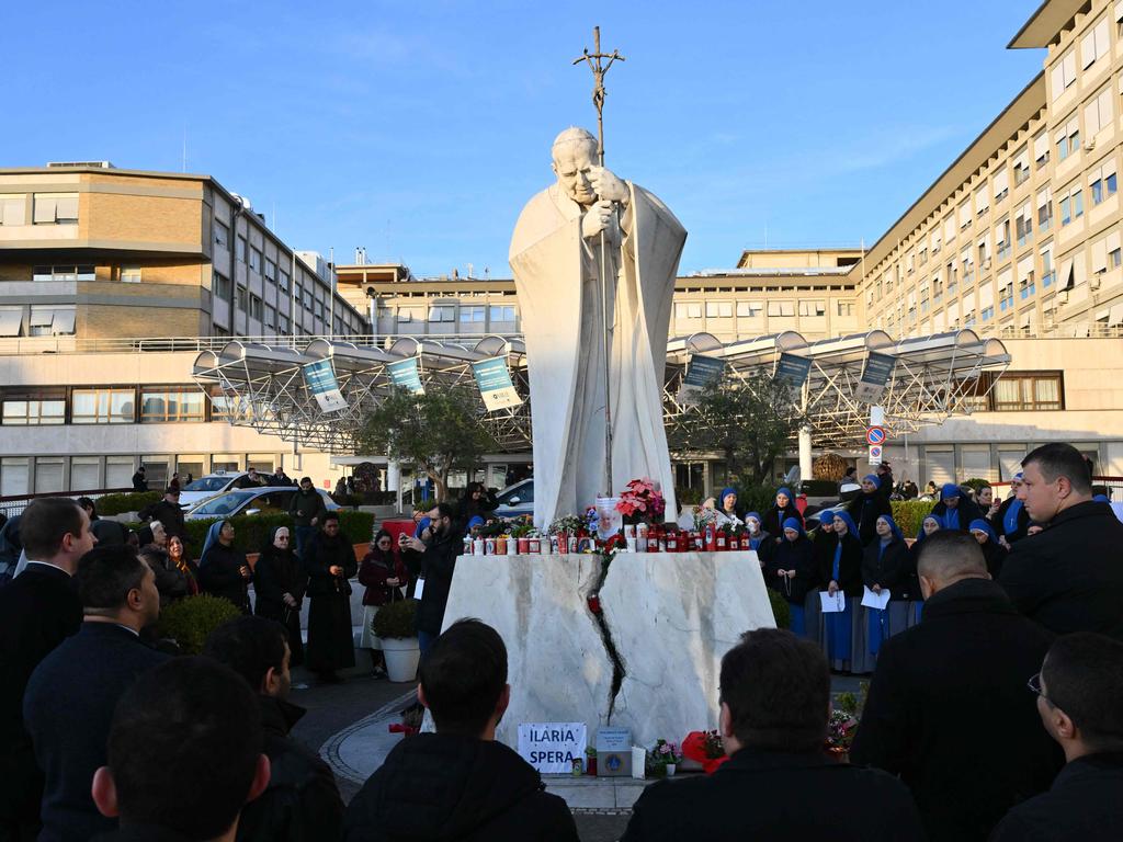 People pray at the statue of John Paul II outside the Gemelli hospital where Pope Francis is being cared for in Rome. Picture: AFP