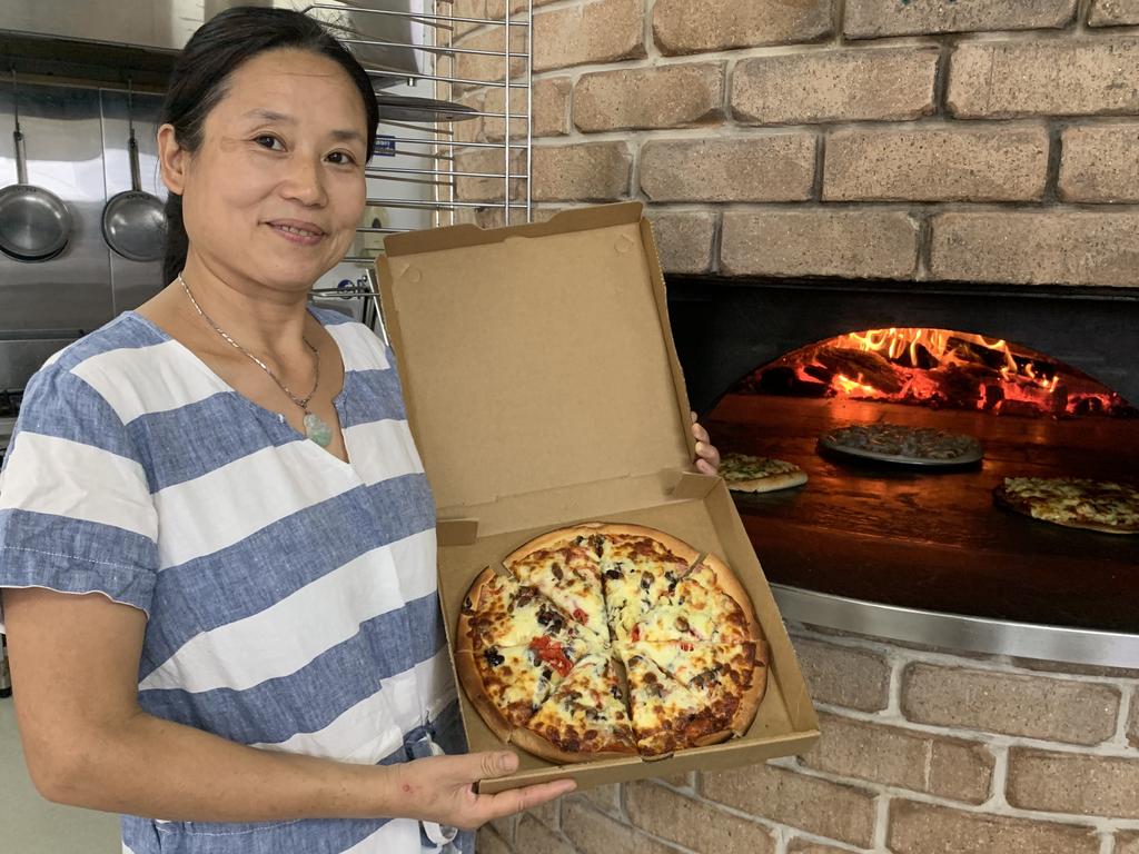 Xiao Dan "Danni" He from Fresh Woodfire Pizza and Pasta in Maryborough displays a freshly cooked pizza beside her pizza oven. Picture: Stuart Fast