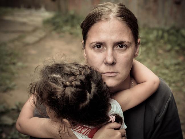 A woman holds a child, trying to calm him down. The child is three years.