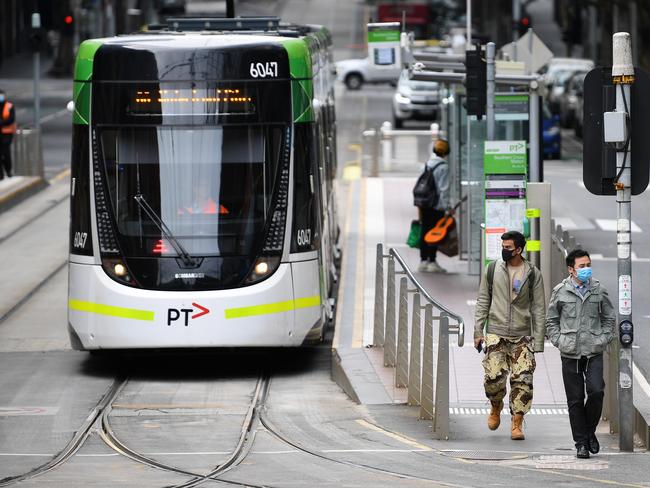 People wearing face masks as a preventive measure against Coronavirus are seen after disembarking a tram in Melbourne, Monday, April 6, 2020. Stage three social distancing measures are now in force throughout Victoria. (AAP Image/James Ross) NO ARCHIVING