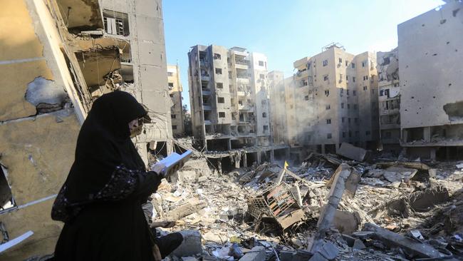 A woman reads the Koran as she stands in front of the smouldering rubble of buildings which were levelled on September 27 by Israeli strikes that targeted and killed Hezbollah leader Hassan Nasrallah. Picture: AFP