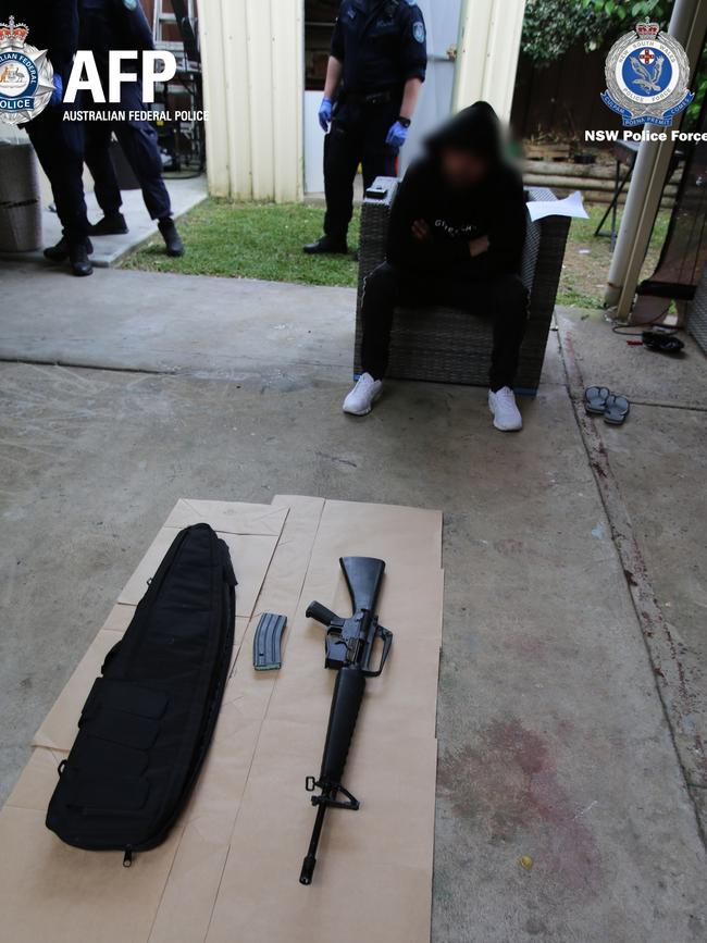 The 27-year-old watches on as police catalogue weapons allegedly found at the Old Guildford home. Picture: NSW Police Media