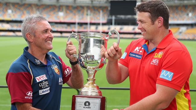 Suns coach Stuart Dew (right) holds the QClash trophy with Brisbane coach Chris Fagan. Picture: Peter Wallis