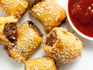 Homemade sausage rolls with sesame seeds and tomato sauce.