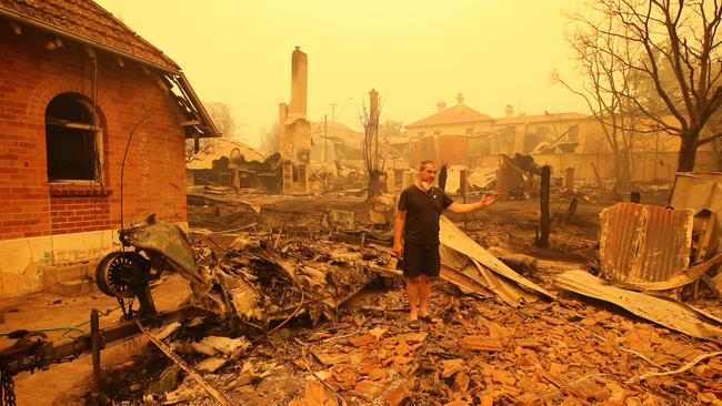 Gary Hinton surveys the debris, including his father’s boat, in Cobargo after a firestorm swept through the area on Wednesday. Picture: Stuart McEvoy