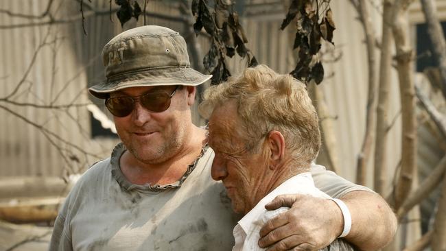 Rex is comforted by Kelvin Henwood as he surveys the wreckage of his home. Picture: Darrian Traynor/Getty Images