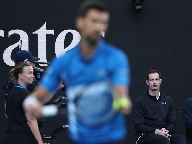 Murray watches on as Djokovic prepares to serve.