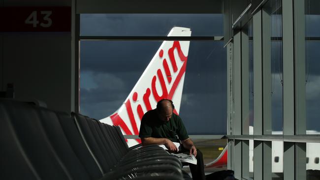 Bloomberg Photo Service 'Best of the Week': A passenger reads a newspaper in a departure lounge as a Virgin Australia Holdings Ltd. aircraft stands on the tarmac at the domestic terminal at Sydney Airport in Sydney, Australia, on Wednesday, Aug. 27, 2014. Virgin Australia, the nation's second-largest carrier, is scheduled to report full-year results on Aug. 29. Photographer: Brendon Thorne/Bloomberg