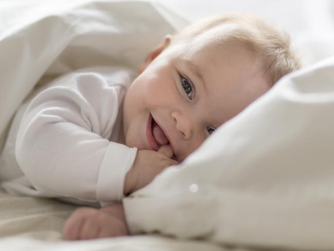 A Cute happy 7 month baby girl in diaper lying and playing