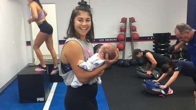 F45 Southport trainer Morgan Meredith holds five week old baby Nephi, as his mum Manawa Ruki and a whole class trains.