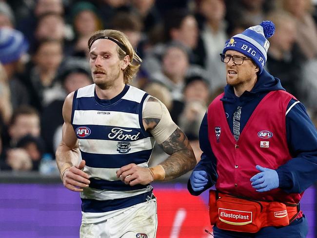 Tom Stewart of the Cats is helped from the field after a heavy collision on Friday night. Picture: Michael Willson/AFL Photos via Getty Images.