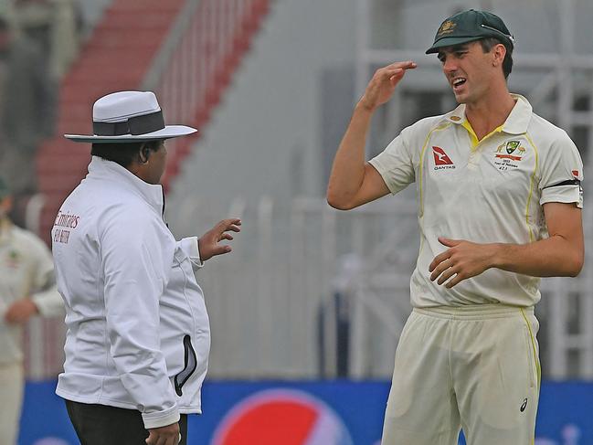 Australia's captain Pat Cummins (R) speaks with field umpire Ahsan Raza after Pakistan declared their first inning during the second day of play of the first Test cricket match between Pakistan and Australia at the Rawalpindi Cricket Stadium in Rawalpindi on March 5, 2022. (Photo by Aamir QURESHI / AFP)