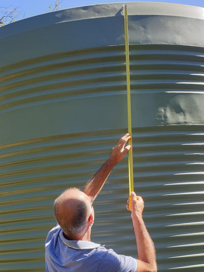 Branko Soda measures the rainwater tank put next to his home. Picture: Colin James