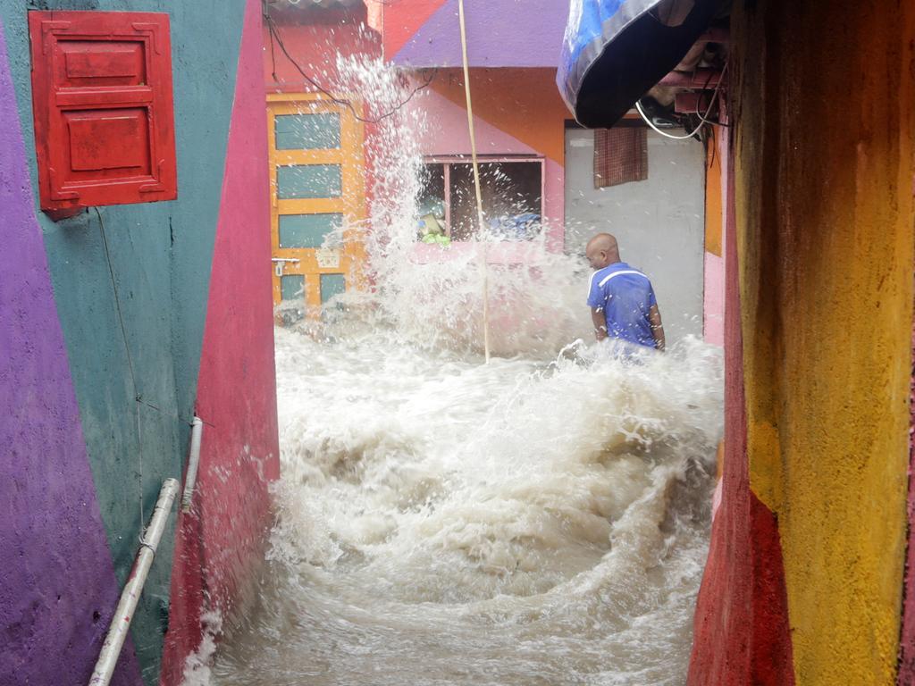 Waves caused by high tide envelops a man standing outside his house near the Arabian Sea in Mumbai, India, Saturday, July 14, 2018. The man was washed away by the wave and rescued by locals about 100 meters away from the spot. (AP Photo/Rajanish Kakade)
