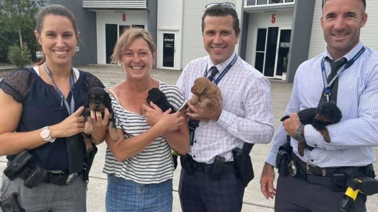 Jeni Merry with her returned puppies and the police officers who helped get the animals home. Picture: Missing and Stolen Pets Australia.