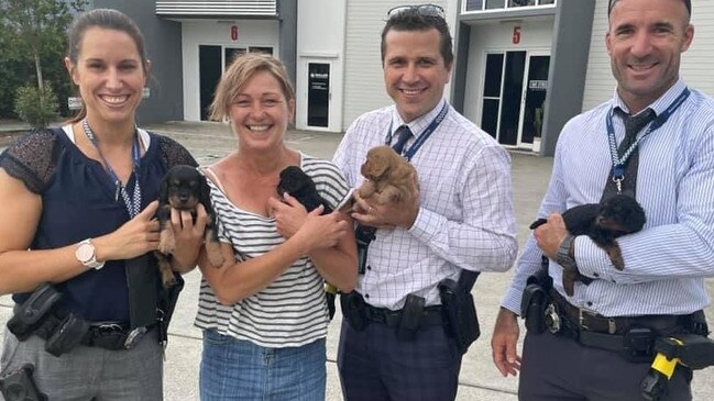 Jeni Merry with her returned puppies and the police officers who helped get the animals home. Picture: Missing and Stolen Pets Australia.