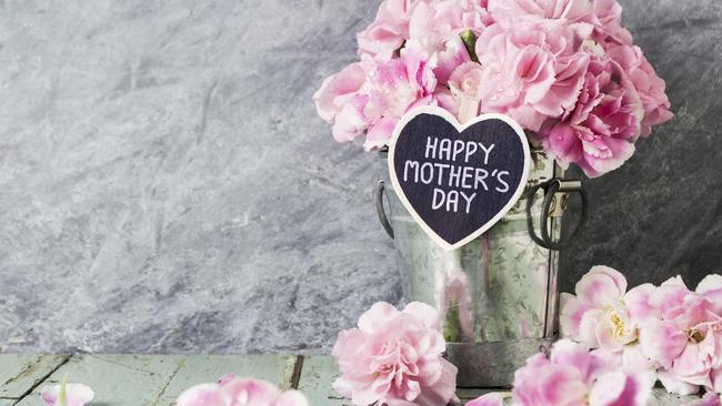 Pink carnation flowers in zinc bucket with happy mothers day letter on wood heart. iStock generic Mother's Day