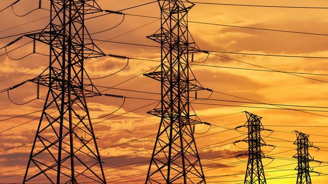 Vibrant evening sun setting behind a row of electrical towers for running high voltage cables.