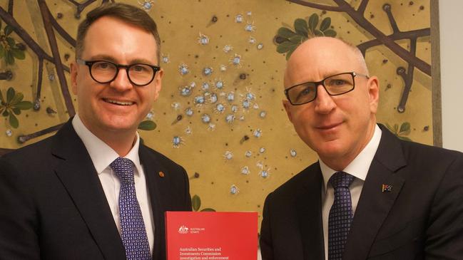 Senator Andrew Bragg hands Coalition financial services spokesman Luke Howarth a copy of his report into ASIC.