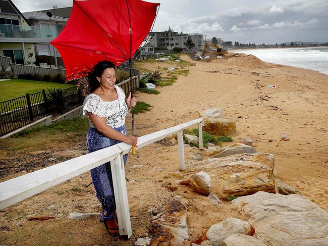 Monica Mark holds an umbrella in front of the sea wall that is under construction at Collaroy in anticipation of the forecast torrential rain and wild weather that is due to hit Sydney on Saturday. Picture: Toby Zerna