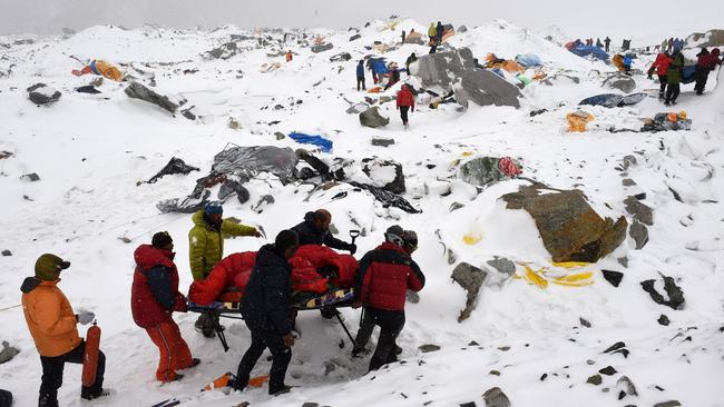 Difficult operation ... rescuers use a makeshift stretcher to carry an injured person after an avalanche flattened parts of Everest base camp following the earthquake. Picture: AFP Photo