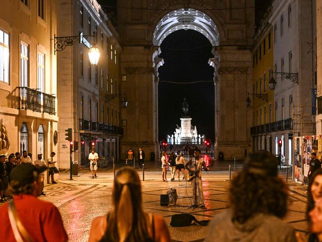 People enjoy music played by street artists at Rua Augusta after the lights were restored following a massive power cut affecting the entire Iberian peninsula and the south of France, in Lisbon on April 28, 2025. Spanish Prime Minister Pedro Sanchez said today authorities were not ruling out any  cause for the widespread blackout across the Iberian pensisula. 
