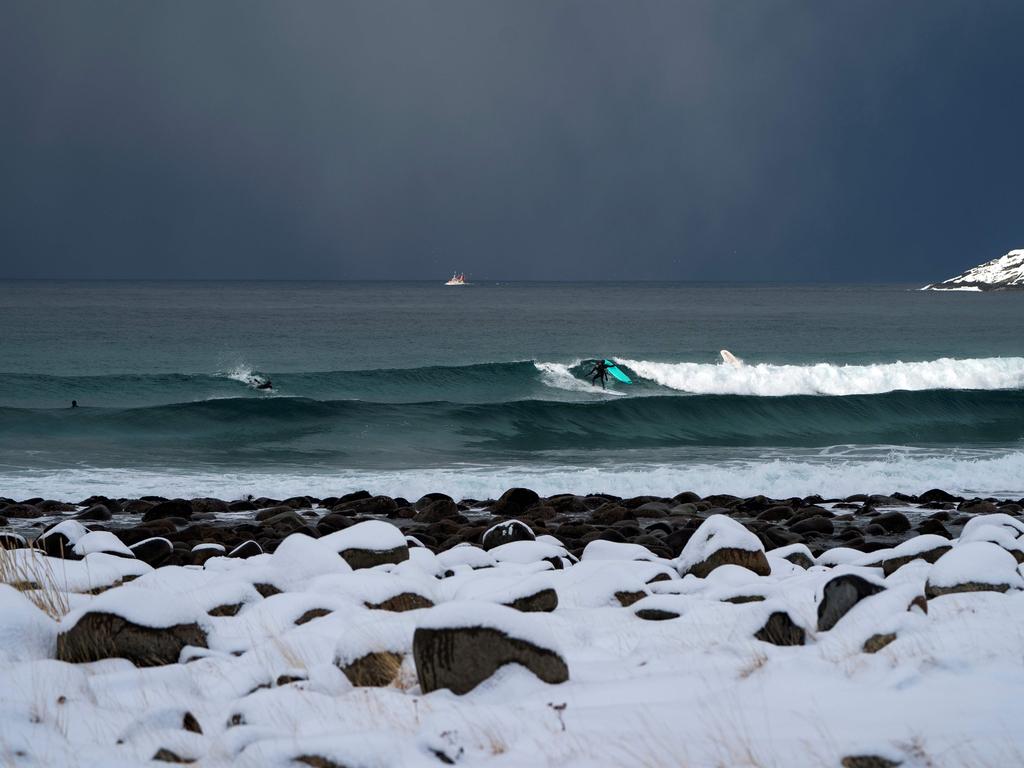 A surfers rides a wave after a sudden snowfall on March 11, 2018 in Unstad, northern Norway, Lofoten islands, within the Arctic Circle. Picture: AFP