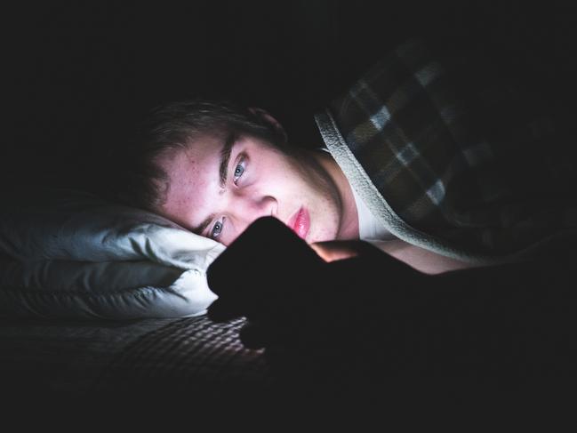 Generic image of child in bed with mobile phone