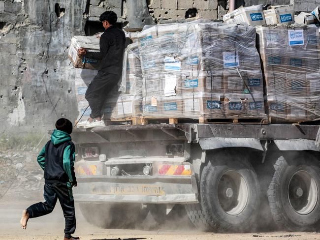 A boy chases one of the trucks carrying humanitarian aid by A boy chases one of the trucks carrying humanitarian aid by the United Nations Relief and Works Agency for Palestine Refugees (UNRWA) coming in from the Kerem Shalom border crossing (also known as Karem Abu Salem) and arriving in al-Shoka, east of Rafah in the southern Gaza Strip on January 21, 2025 following a ceasefire deal in the war between Israel and Hamas in the Palestinian territory. (Photo by Bashar TALEB / AFP)