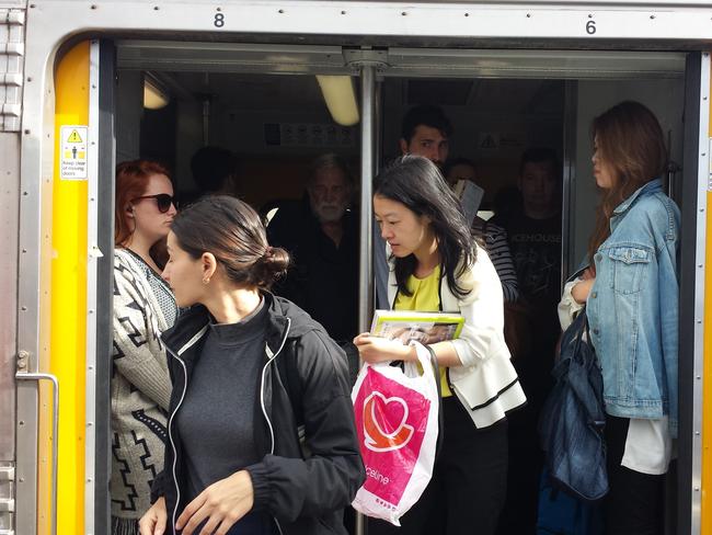 Commuters spill out of a crowded morning train as many more prepare to board at Macdonaldtown.