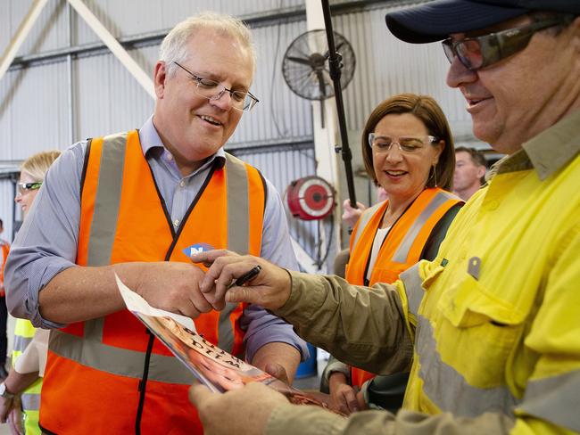 GOLD COAST, AUSTRALIA - NewsWire Photos October 10, 2020: The Prime Minister Scott Morrison signs a photograph of Darren Tonks (right) grandchild. Darren hasn't seen his grandchild for ages because of COVID restrictions. The Prime Minister and Queensland LNP opposition leader Deb Frecklington visited Neumann Steel on the Gold Coast to further promote jobs in the lead-up to the Queensland state election.  Picture: NCA NewsWire / Sarah Marshall