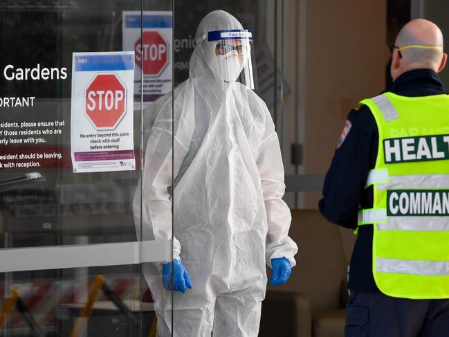 Medical workers speak at the entrance to the aged care facility. Picture: AFP