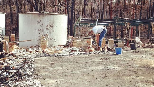 Bob Gorringe works to clear the rubble from his razed home at Nymboida.