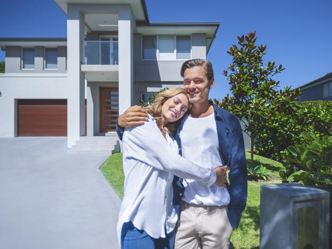 Couple standing in front of their new home.  mortgage generic