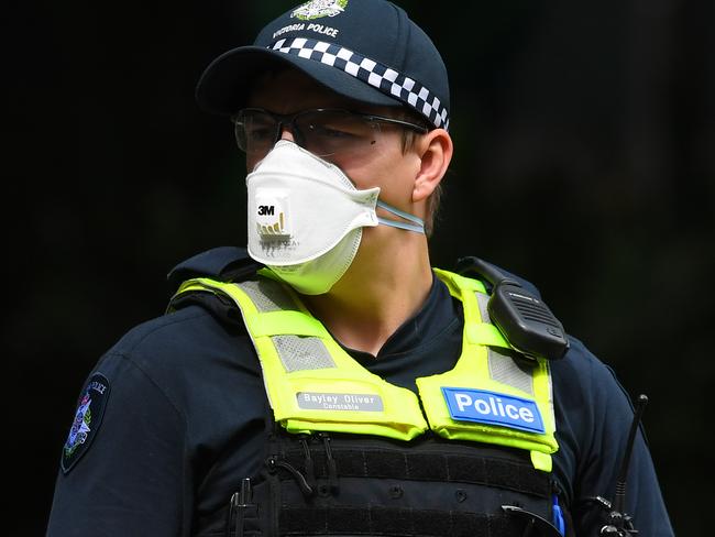 A Victorian Police officer wearing a face mask is seen outside of Crown Metropol Hotel in Melbourne, Monday, March 30, 2020. Travellers and Australian residents who arrive into the country from overseas are being sent straight to makeshift quarantine facilities across Australia. Travellers will spend 14 days of quarantine in state-funded hotel rooms, with doors guarded by state police, defence personnel or private security guards.(AAP Image/Bianca De Marchi) NO ARCHIVING