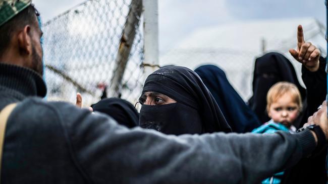 A member of the Syrian Democratic Forces stands before veiled foreign women in al-Hol camp, which houses relatives of Islamic State group members. Picture: AFP