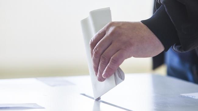 Hand of a person casting a ballot at a polling station during voting. election voting vote polling poll generic Townsville