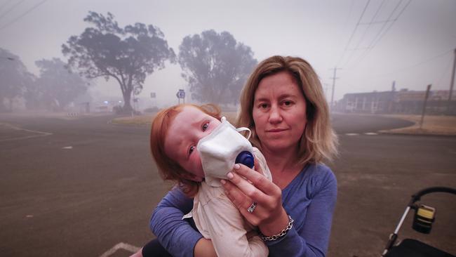 Many children holidaying are having trouble with the thick smoke that has settle over the Mallacoota since the start of the fires. Mum Laura Langmead tries to put a breathing mask over her daughter Evie 1, to help filter the smoke. Picture: David Caird