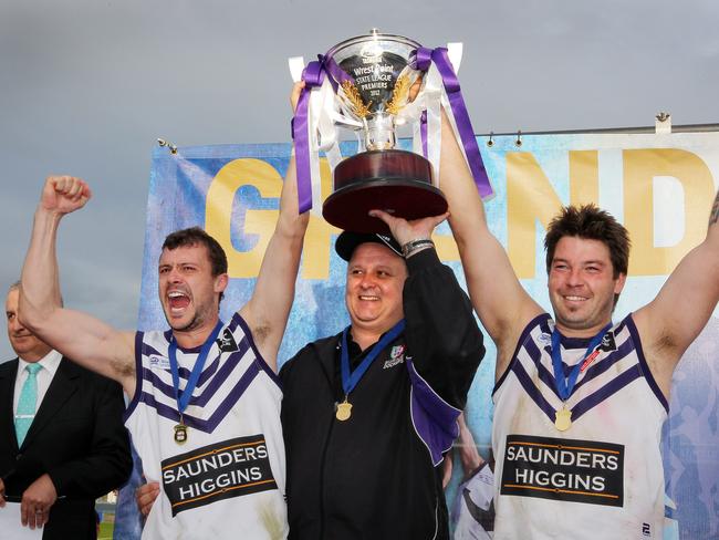 Co-captains Kade Munday (LHS) coach Brent Plant and Luke Shackleton celebrate their 2012 TSL grand final win.