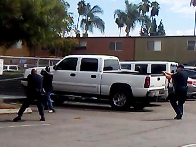 In this Tuesday frame from video provided by the El Cajon Police Department, a man, second from left, faces police officers in El Cajon, California. The man reportedly acting erratically at a strip mall in suburban San Diego was shot and killed by police after pulling an object from his pocket, pointing it at officers and assuming a "shooting stance," authorities said. Picture: El Cajon Police Department via AP.