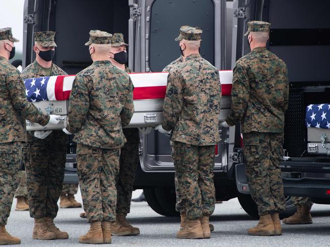 A flag-draped transfer case with the remains of a fallen service member is placed inside a transfer vehicle. Picture: AFP