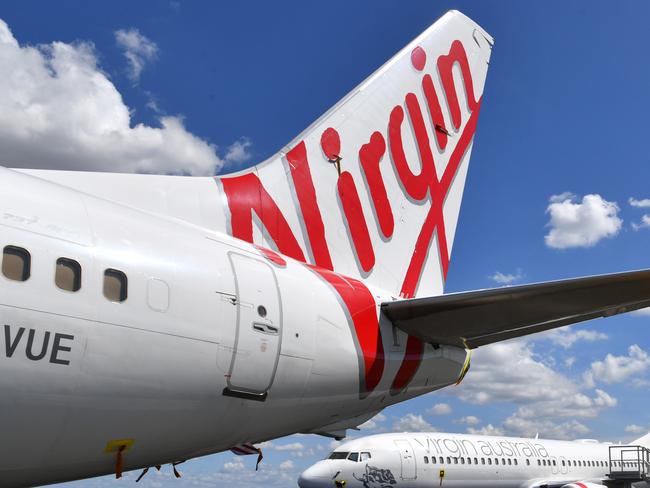 Grounded Virgin Australia aircraft are seen parked at Brisbane Airport in Brisbane, Tuesday, April 7, 2020. Brisbane Airport Corporation (BAC) is working with airlines by accommodating up to 100 grounded aircraft free of charge in response to government-mandated travel restrictions that have grounded a significant proportion of Australia's airline fleet because of the Coronavirus (COVID-19). (AAP Image/Darren England) NO ARCHIVING