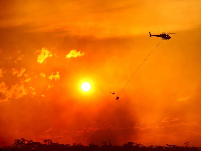 Helicopters water bomb the bushfire at Alfords Point and Menai on Sunday. Picture: Damian Shaw