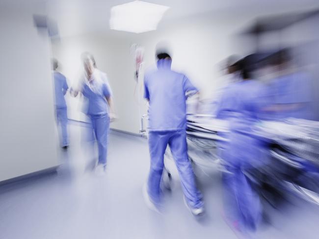 Doctors and nurses pulling hospital trolley,