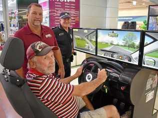 TEST DRIVE: Alan Weeton tries out the driving simulator for Road Safety Week with Greg Caletti, from the Maranoa PCYC, and Senior Constable Dale Kenna, of Roma Police. Picture: Jorja McDonnell